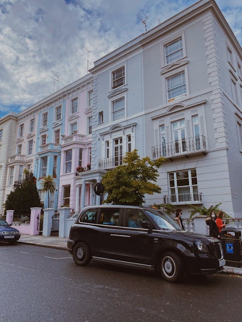 A row of Victorian terraced houses on Pembridge Villas in Notting Hill, featuring pastel-colored facades in shades of pink, blue, and cream with decorative white trim and bay windows. The buildings ha